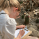 Kind tekent zittend omringd door cactussen